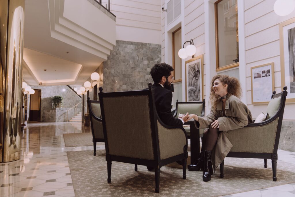 A couple sitting on armchairs talking, discovering how to make a man fall in love naturally.