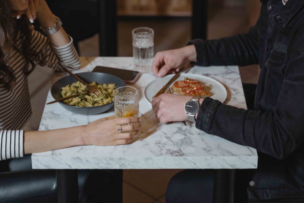 Close up of a couple at a cafe table mirroring hand gestures, discovering how to get your crush to like you.