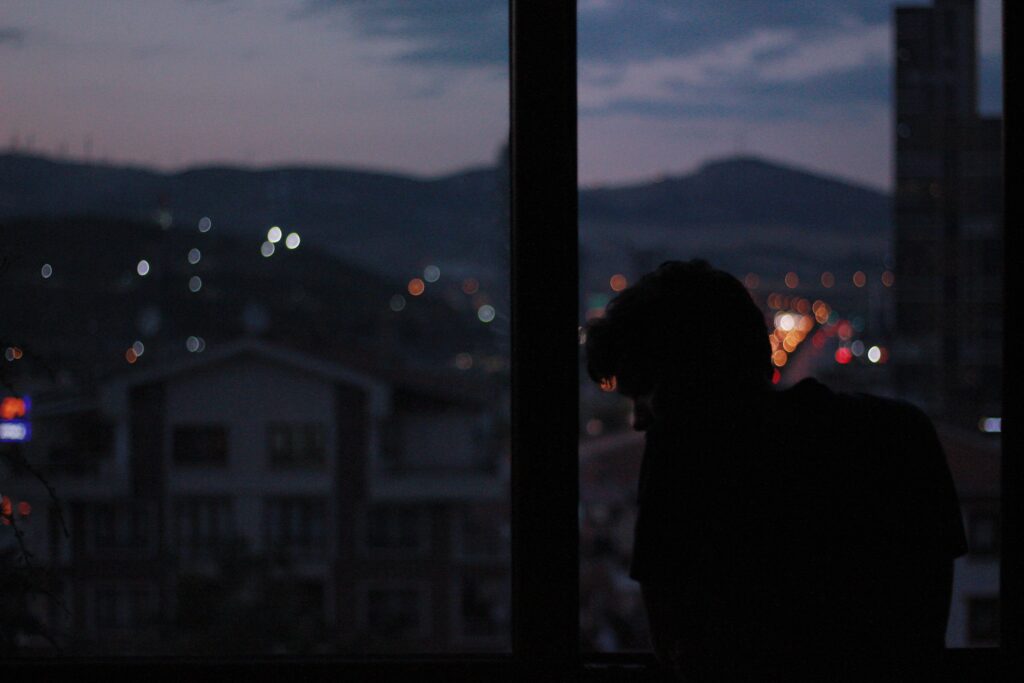 Silhouette of a man staring out a window, processing emotions when my boyfriend avoids me during a fight.