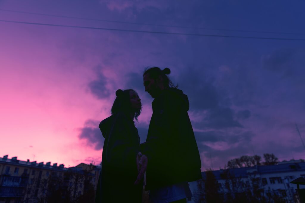 Silhouette of a couple facing each other at sunset, capturing expressing deep feelings for the first time. 