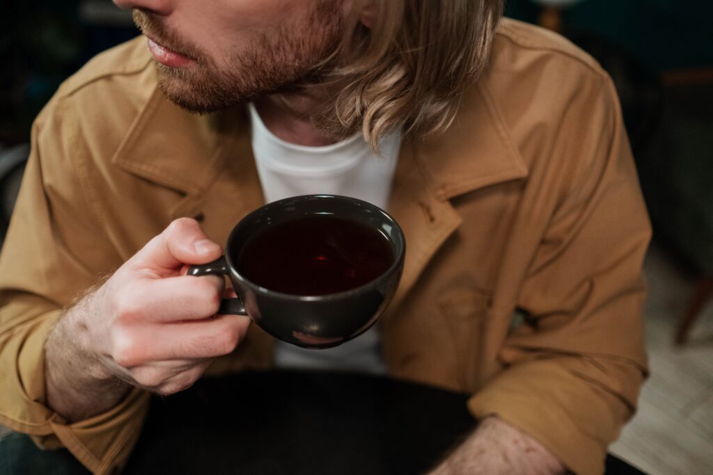 Close up of a man holding a coffee cup while considering how to tell someone you like them over a date.