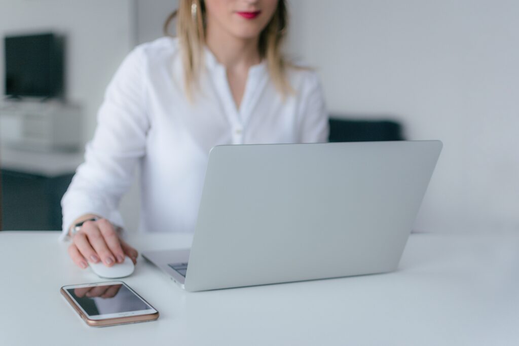 A focused woman working on a laptop with her phone down, building a high-value boundary.