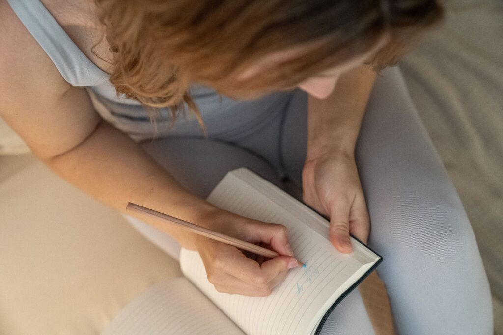 Top view of a woman writing in a notebook to process her overwhelming distant boyfriend anxiety.