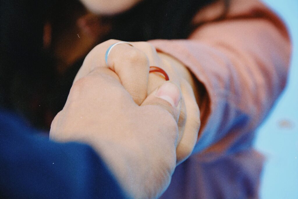 Close up of a couple holding hands, showing authentic connection over how to make someone like you tactics.