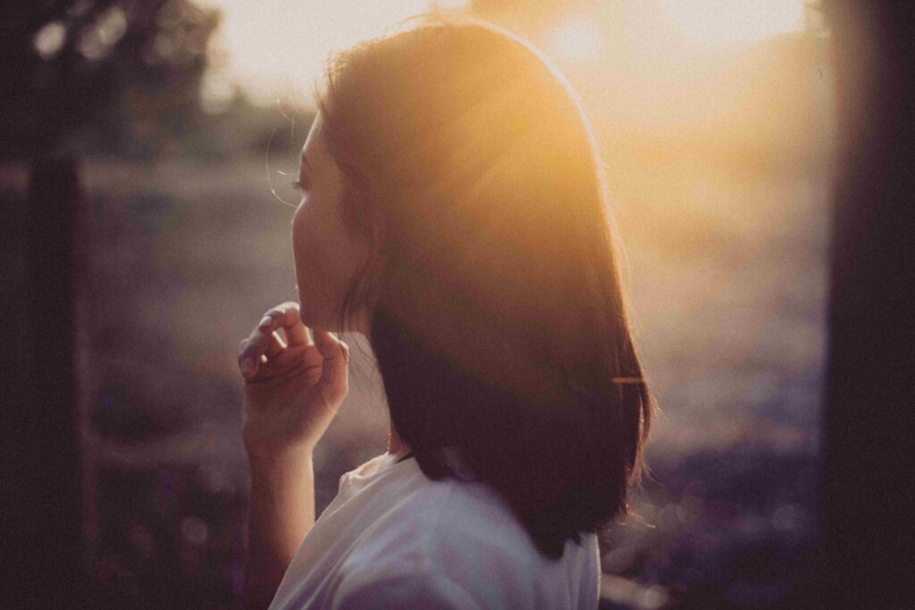 Side profile of a pensive woman at sunset, experiencing intense relationship insecurity.