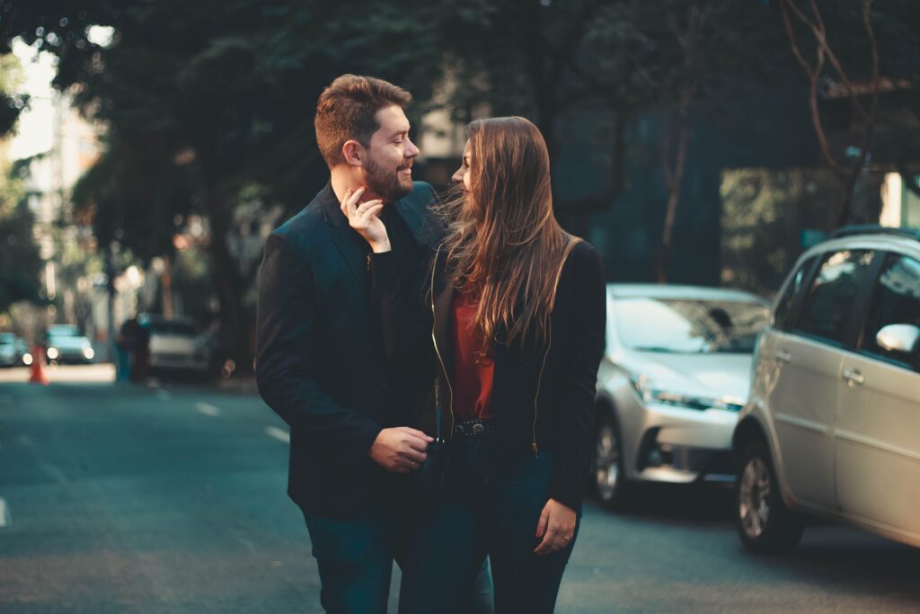 A smiling couple sharing a warm, emotional connection outdoors, discovering how to make a guy fall in love.