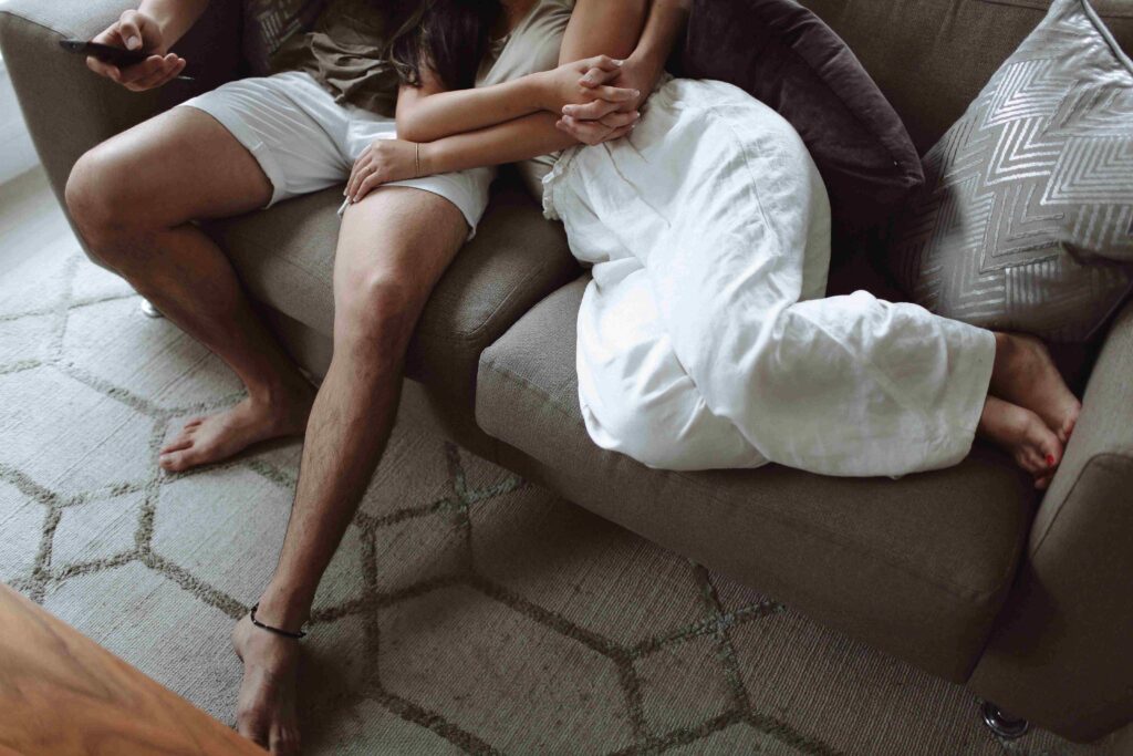 A couple relaxing closely together on a cozy sofa, embracing how to make someone fall in love with you.