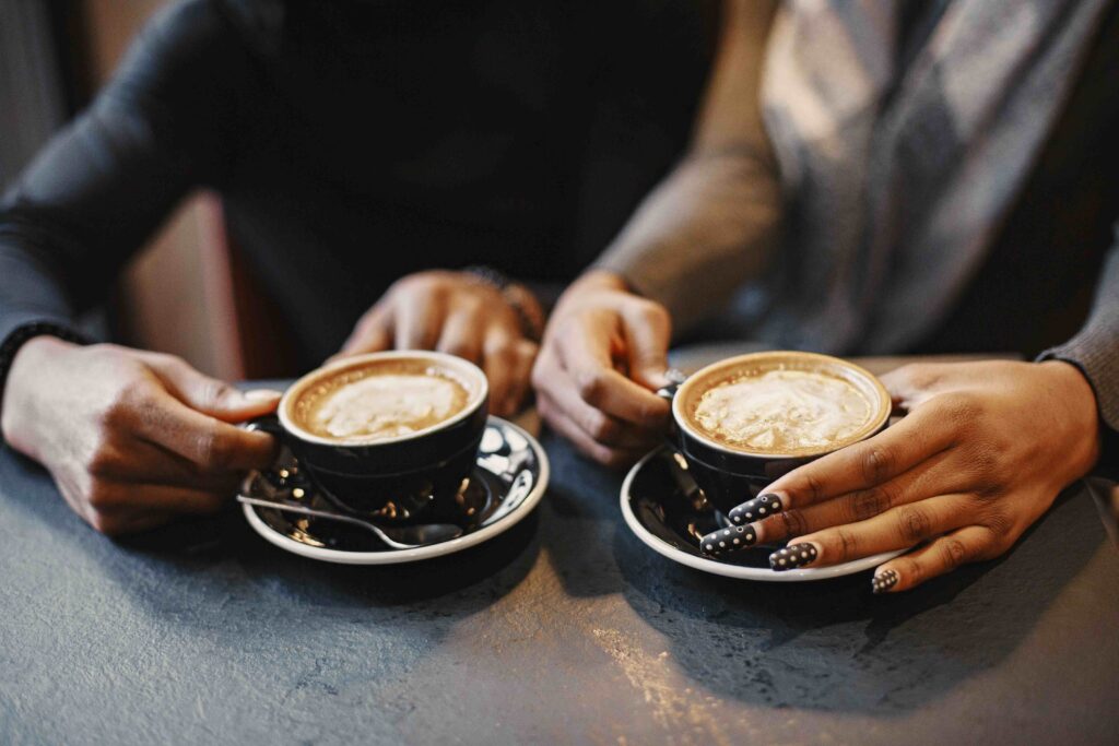 Close up of two hands holding separate coffee cups, understanding how to make him want you.