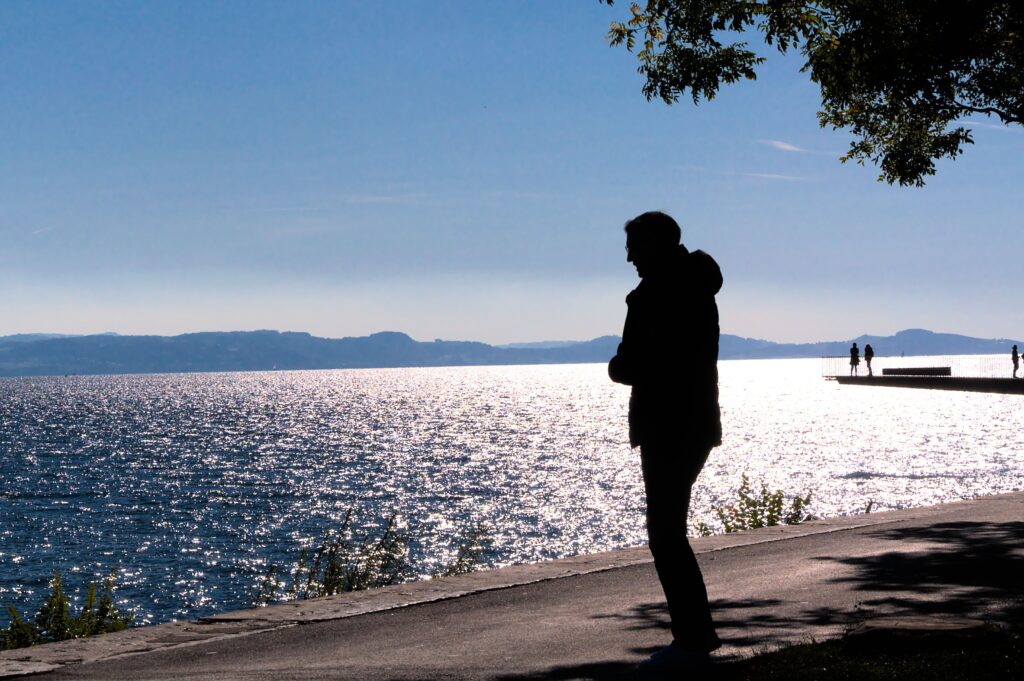 Silhouette of a person walking along the water to escape a cruel girlfriend dynamic and find peace.