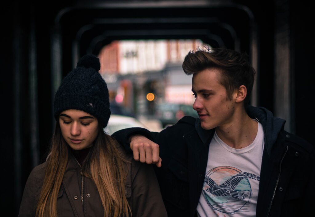 A guy leaning on a railing looking at a woman in a beanie, focusing on attracting a woman naturally.
