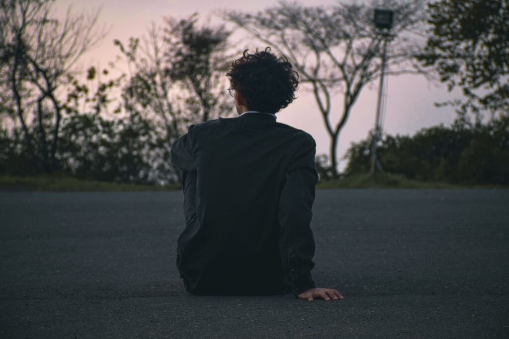 A person sitting alone at dusk reflecting while building personal consistency. 