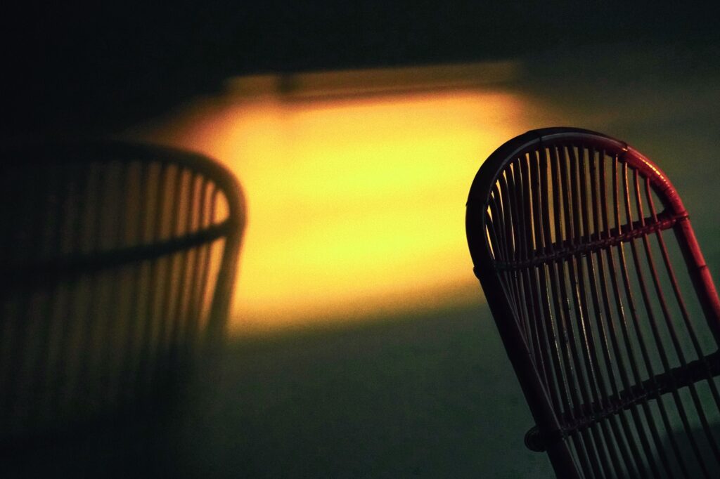 A single wicker chair shadow cast on a warm patch of light, encouraging habits on how to forget about someone.