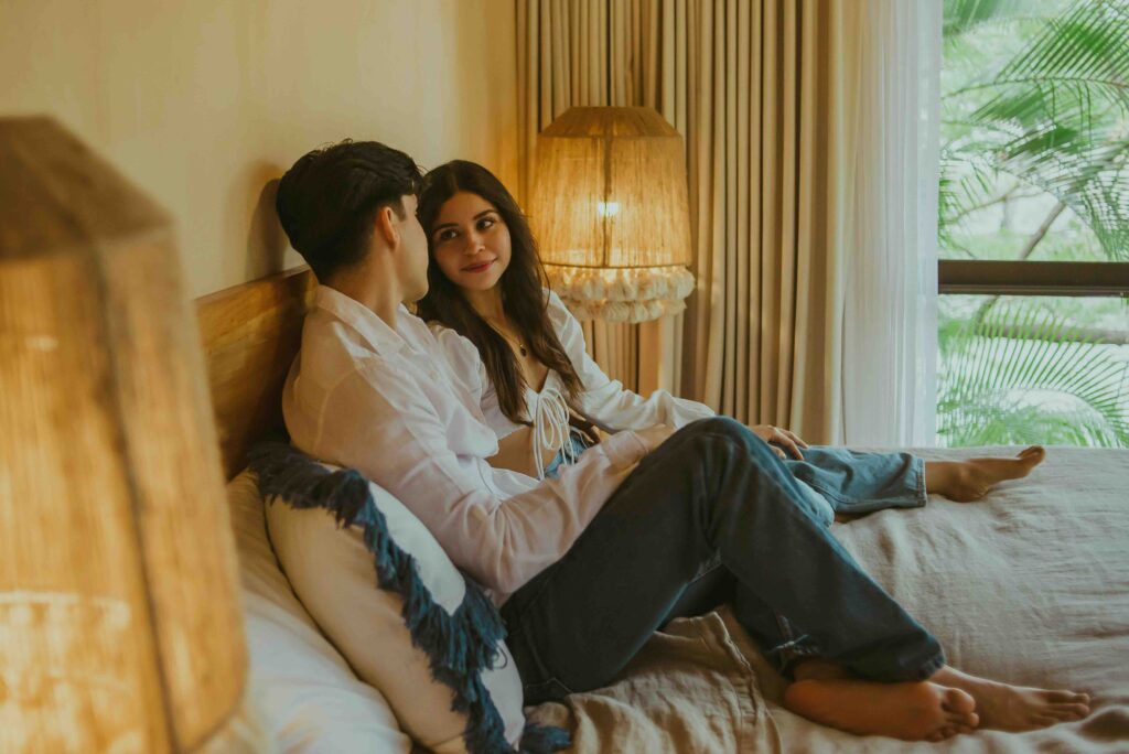 A couple talking on a bed, setting clear personal boundaries and speed limits for what is 2nd base in dating.