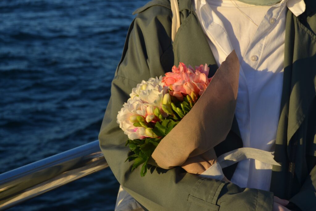 Will I Ever Find Love? 9 Honest Truths About Finding The One A close-up of a person in a trench coat holding a fresh bouquet of flowers, wondering will I ever find love.