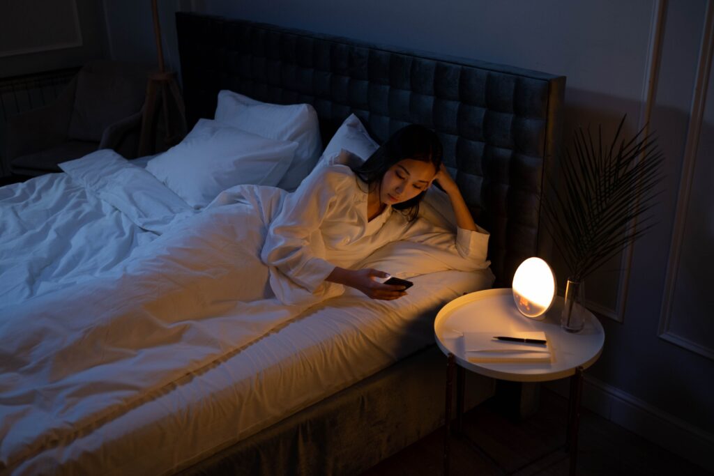 How to Get Over a Crush: A Realistic 14-Day Guide A woman lying in bed at night scrolling on her phone, breaking digital triggers to learn how to get over a crush.
