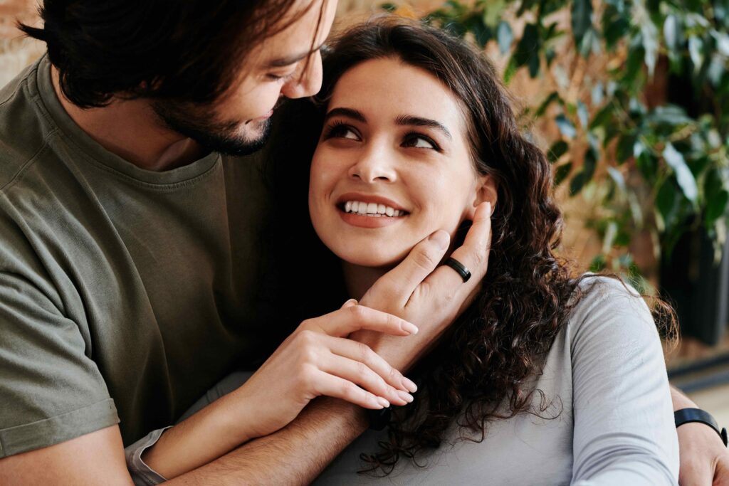 A smiling woman looking lovingly into a man's eyes as he touches her cheek, improving relationship habits.