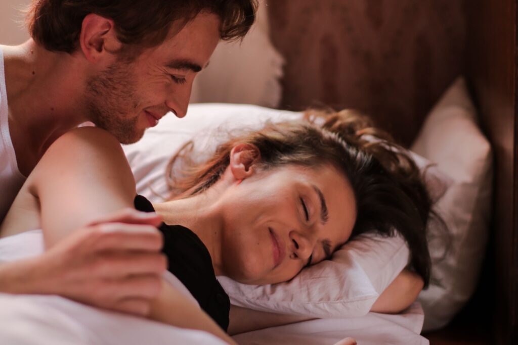 A man looking at a smiling woman closely, practicing post intimacy aftercare for what is third base in dating.