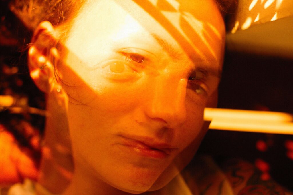 Close-up of a woman's face with dramatic golden sunlight streaming across her eyes, subconscious manifestation of departed souls.