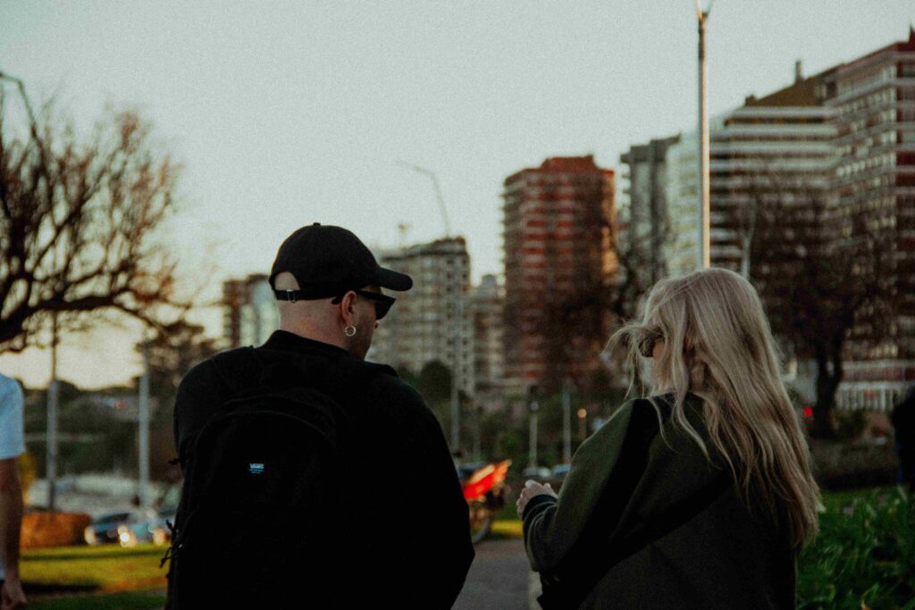 A man and a woman walking in a park at sunset, ending a warm conversation to connect with anyone authentically.