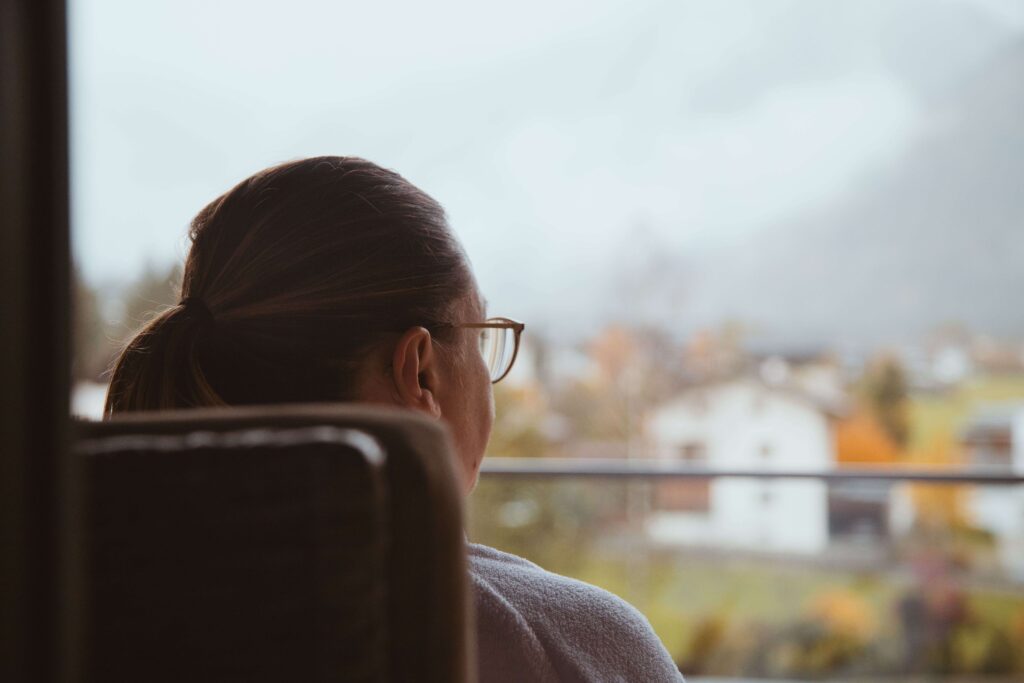 A woman looking out a train window reflecting on self improvement habits. 