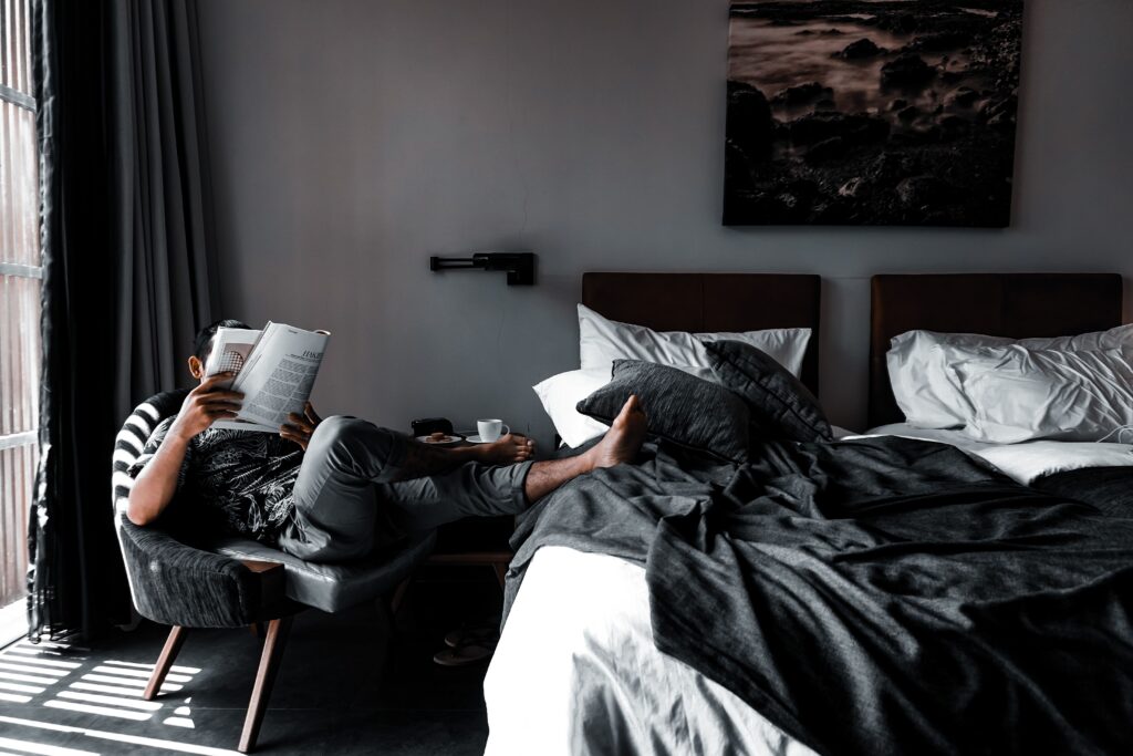 A man reading a book by the bed, embracing a carefree day with peaceful good morning Saturday blessings.