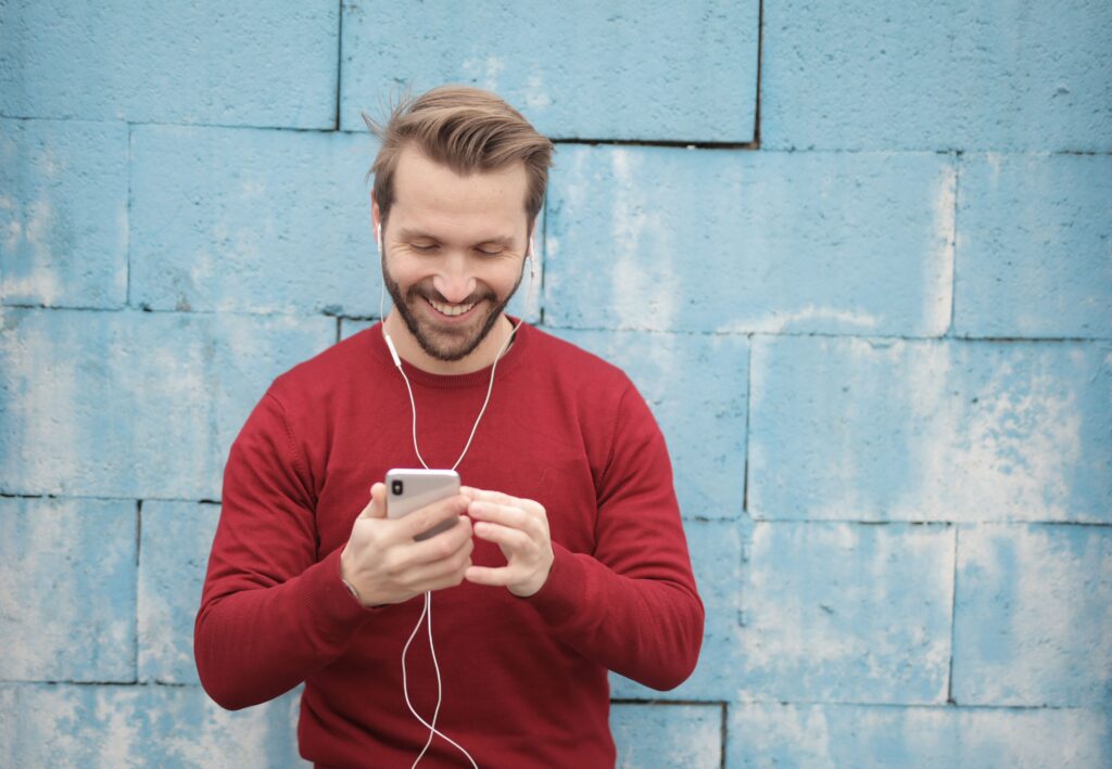 A smiling man reading romantic love poems for husband on his smartphone. 
