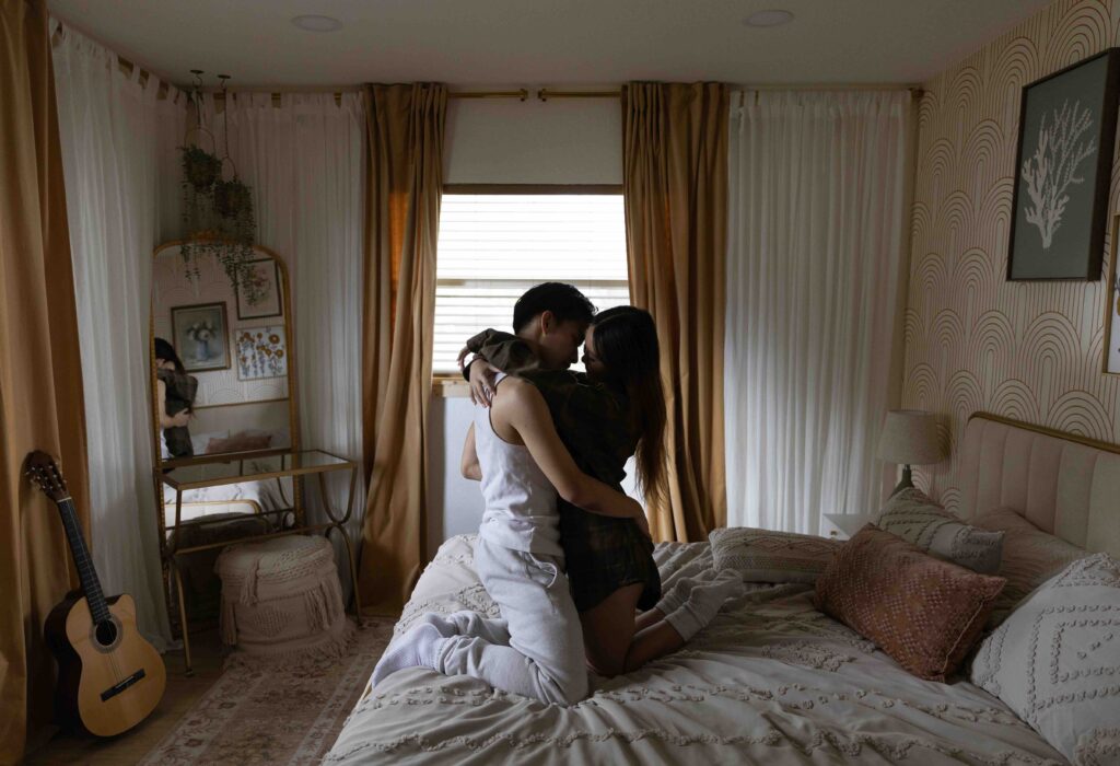 A couple embracing on a bed, focusing on safety and vulnerability while reaching final bases in a relationship.
