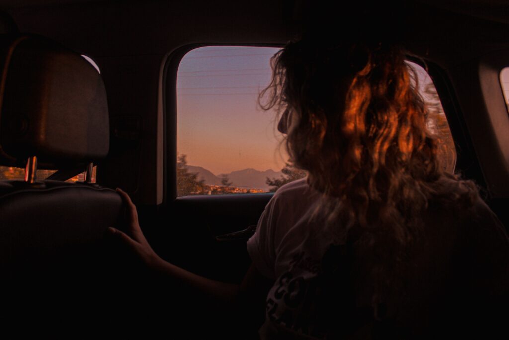 A woman looking out a car window at sunset reading short love poems for boyfriends. 
