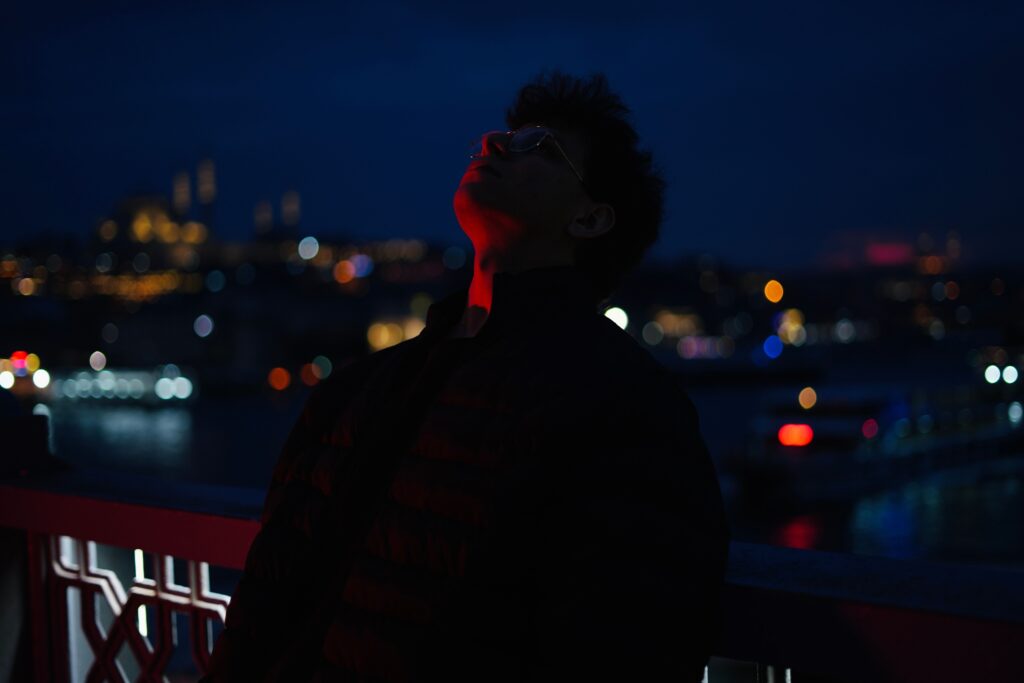 A man standing on a bridge at night looking up at the sky, letting go of long-held barriers to finding love.
