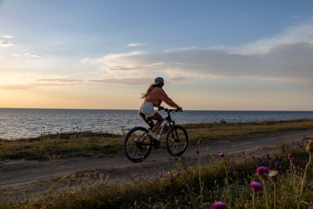 A woman riding her bicycle along a coastal path at sunset, moving forward to let go of a past relationship.