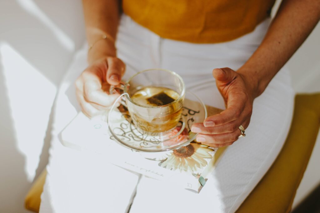 145 Thursday Inspirational Quotes to Finish Strong A woman holding a cup of tea resting on a book, feeling energized by positive Thursday inspirational quotes.