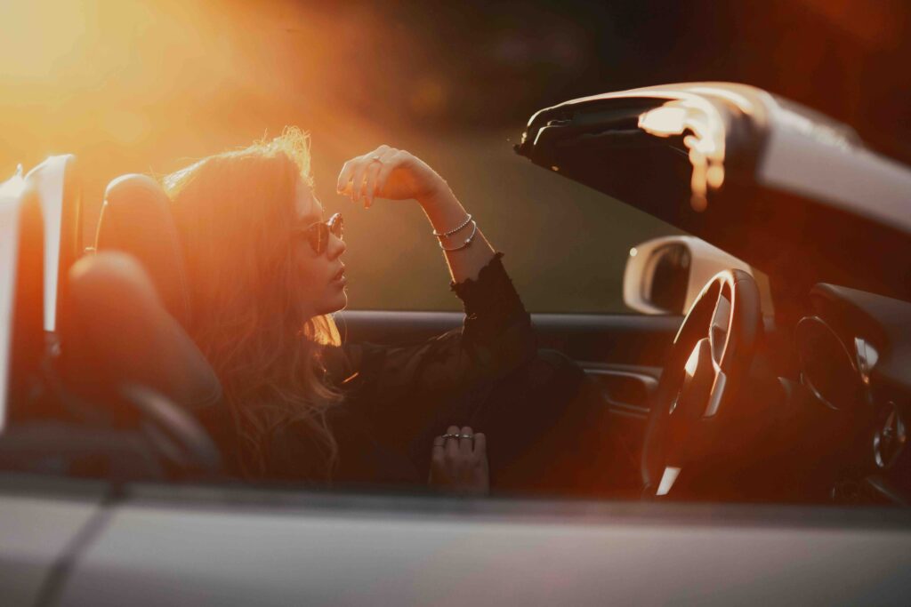 An unbothered woman driving a convertible car at sunset, illustrating the sigma female meaning.