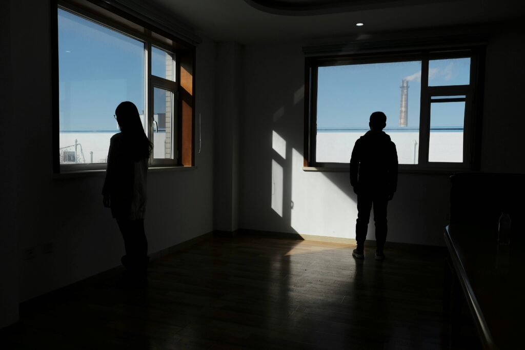 Two people standing separately near windows, illustrating right person wrong time signs. 