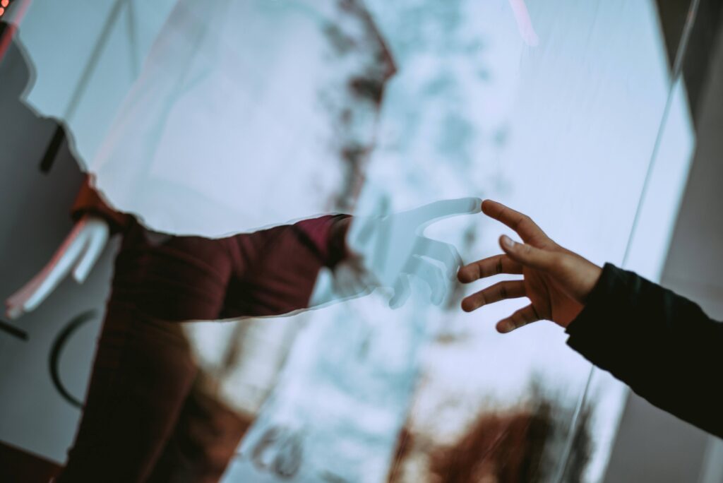 Identity Crisis Meaning: Why We Lose Ourselves & How to Rebuild Hands reaching out across a glass mirror reflecting an identity crisis.
