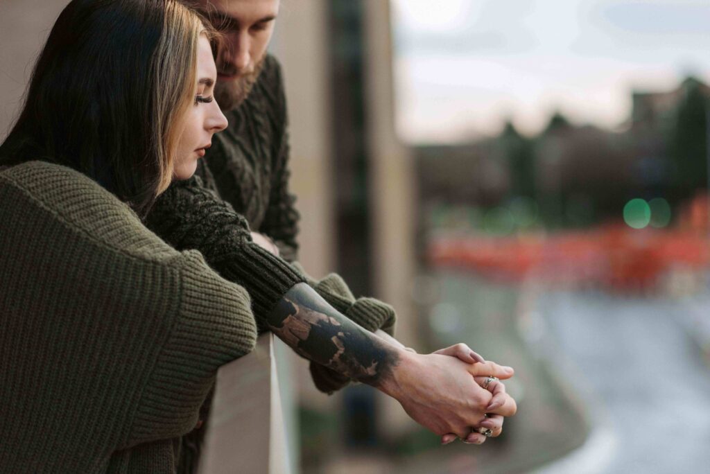 Loving couple holding hands on a balcony while focusing on building eq with your partner together. 