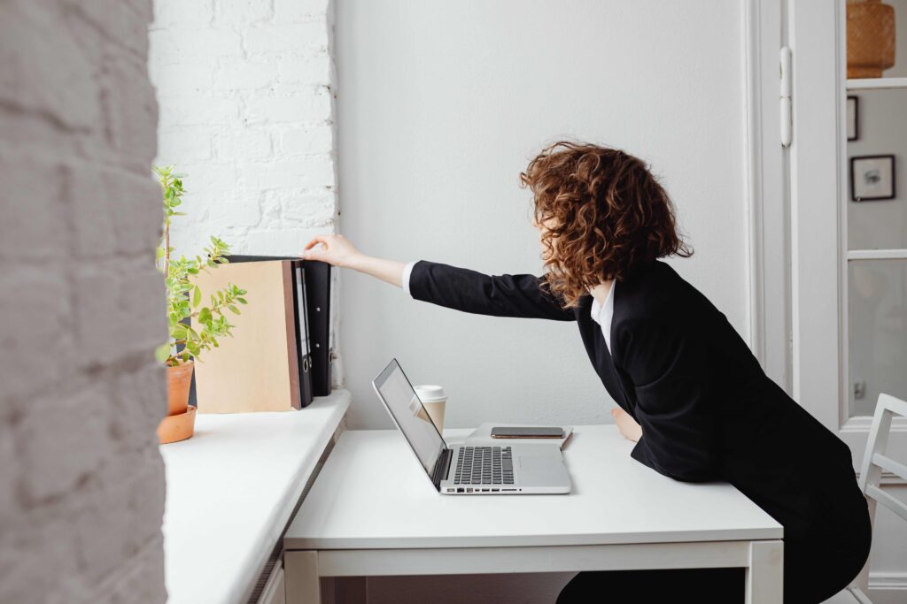 A woman standing near a desk organizing projects after analyzing dreams of pregnant emotions.