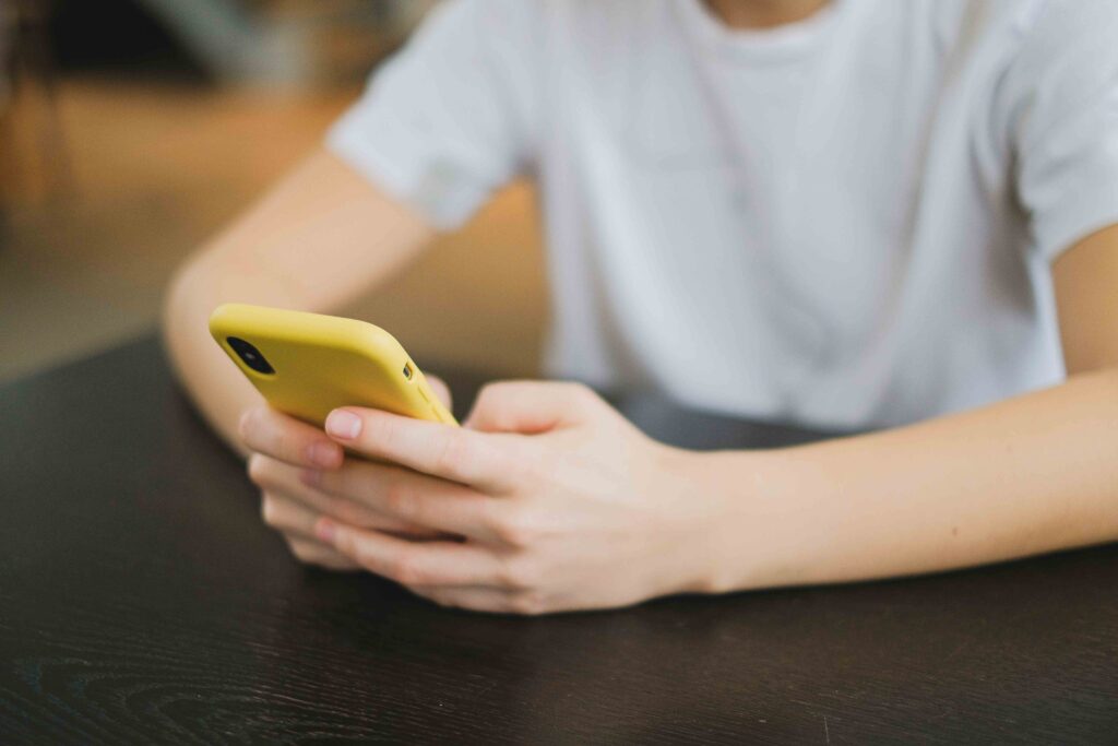 Close up of hands holding the phone representing self-erasure in partnership and digital communication.