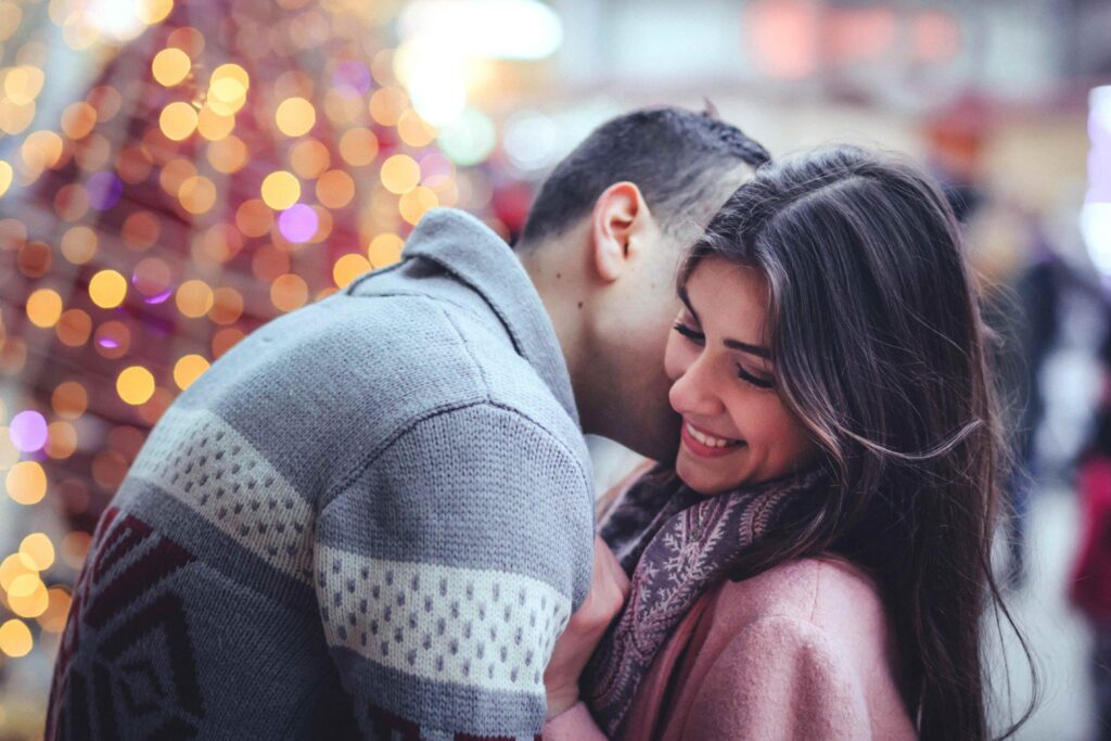 A couple showing healthy physical affection in public outdoors during nighttime. 