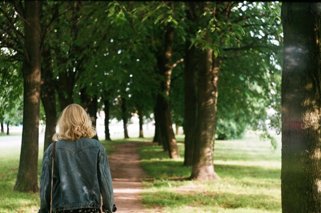 A woman walking in a park learning how to manage emotional sensitivity with nature resets. 