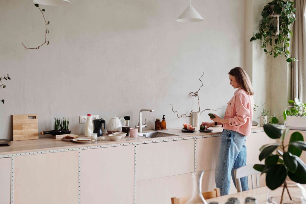 A woman preparing food in a bright modern kitchen practicing self respect in daily life alone.
