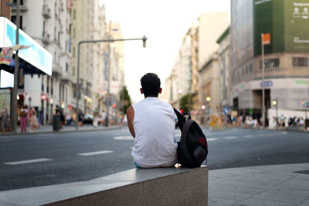 A man sitting alone on a city bench contemplating the definition of a kind person. 