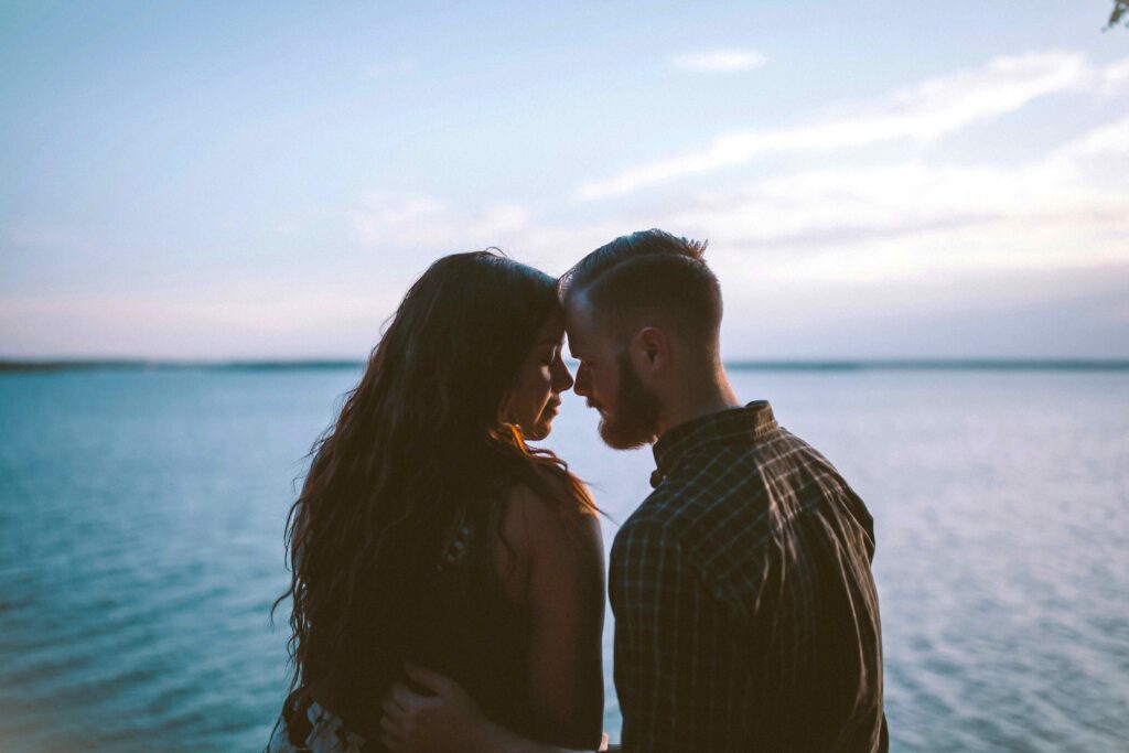 Identity vs Role Confusion in Adults: Staying True in Relationships A couple standing by the water facing each other dealing with identity vs role confusion.