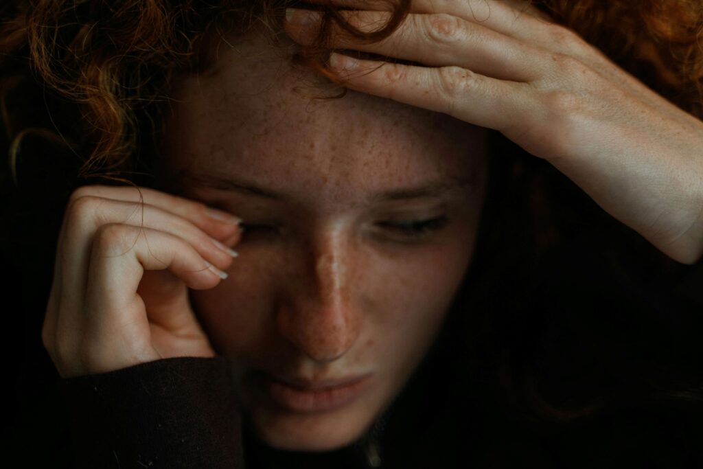 A stressed woman holding her head contemplating identity versus role confusion in love.
