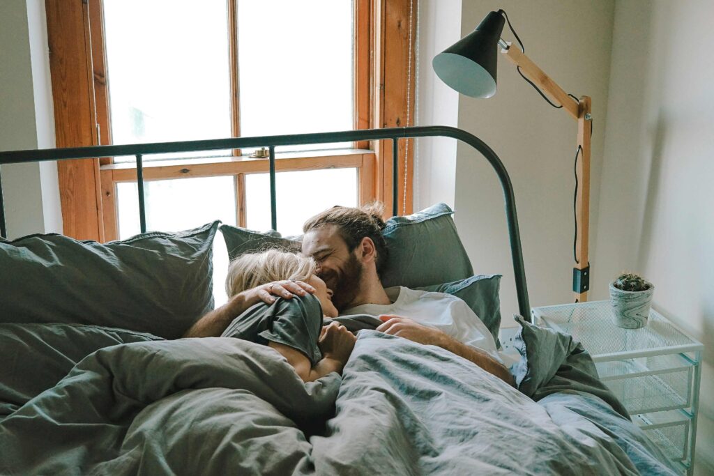 A couple cuddling comfortably in bed expressing the meaning of a kind person. 