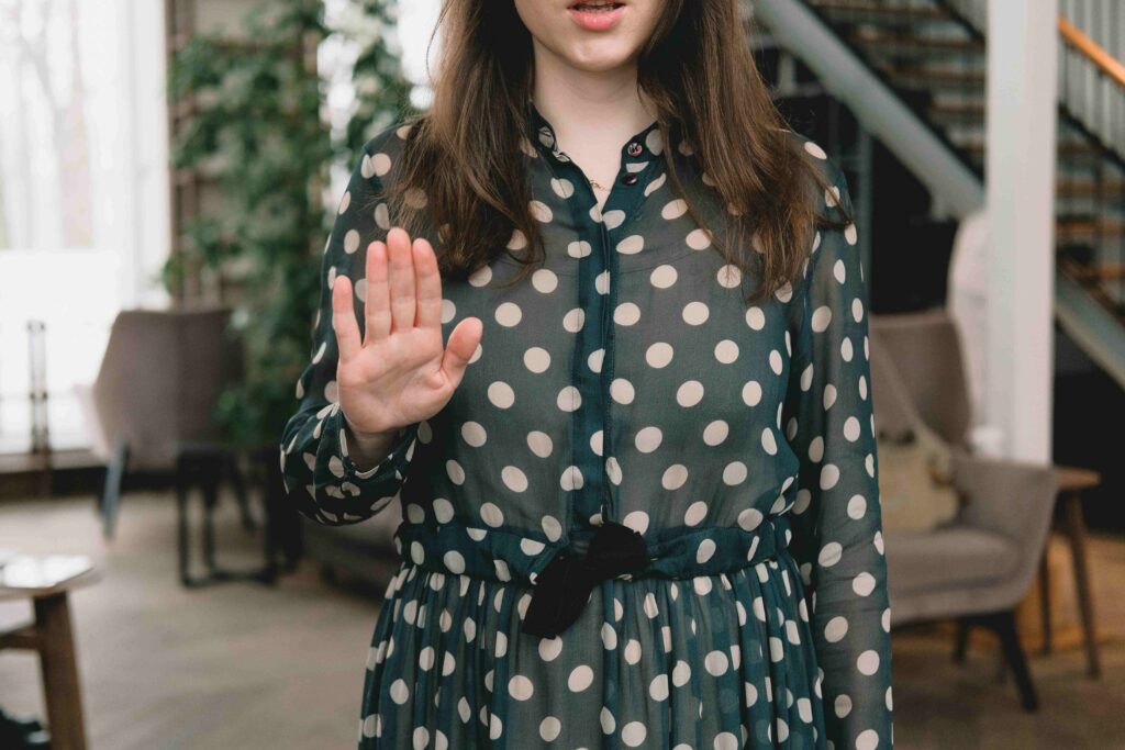 How to Let Someone Down Easy: 9 Kind Scripts to Use Right Now A woman showing a stop gesture learning how to let someone down easy politely.