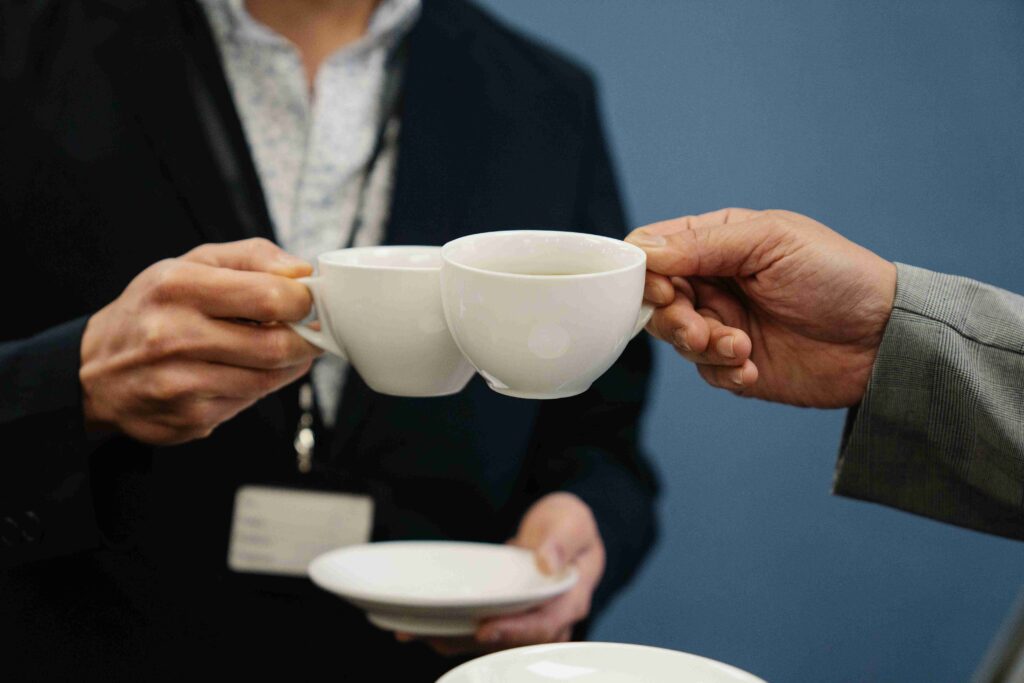 Two professionals clinking coffee cups together overcoming personal identity crisis.