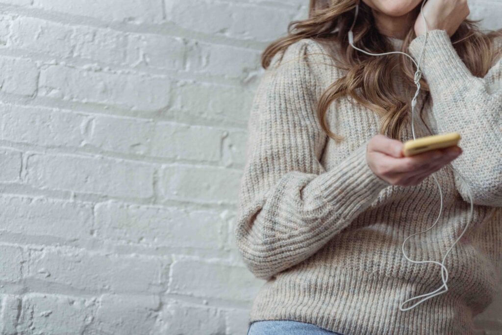 A woman wearing headphones listening to music learning how to stop being clingy. 