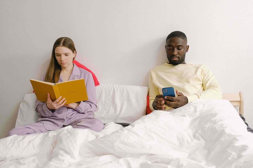 Distant couple sitting on bed illustrating the dynamic of iq vs eq in relationships.