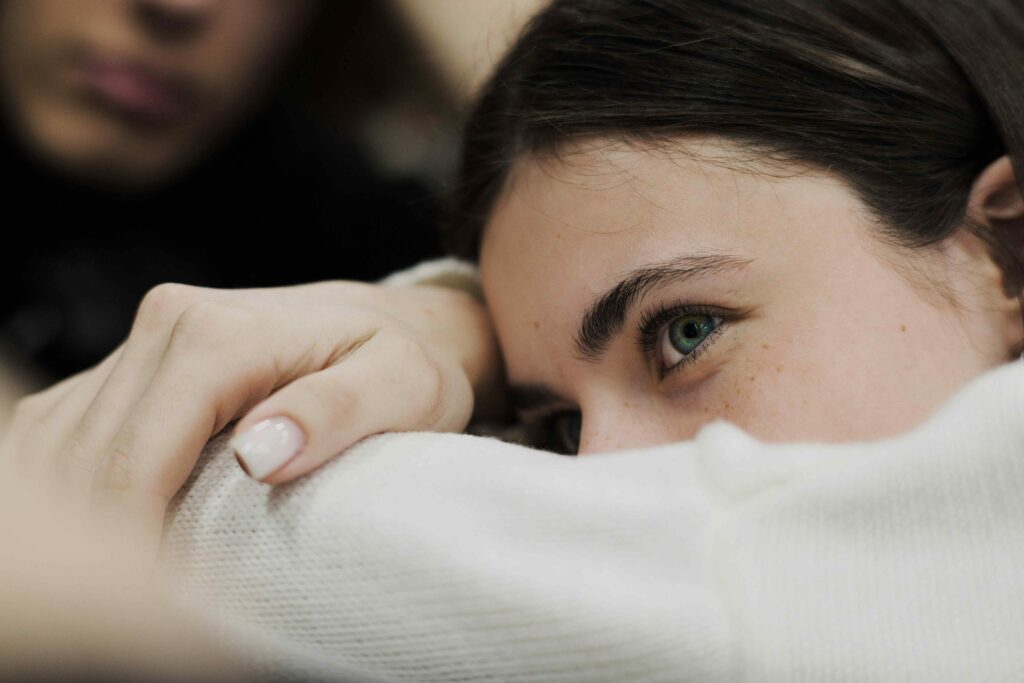 A woman resting her head sadly while recognizing fake friends and quiet emotional distance.