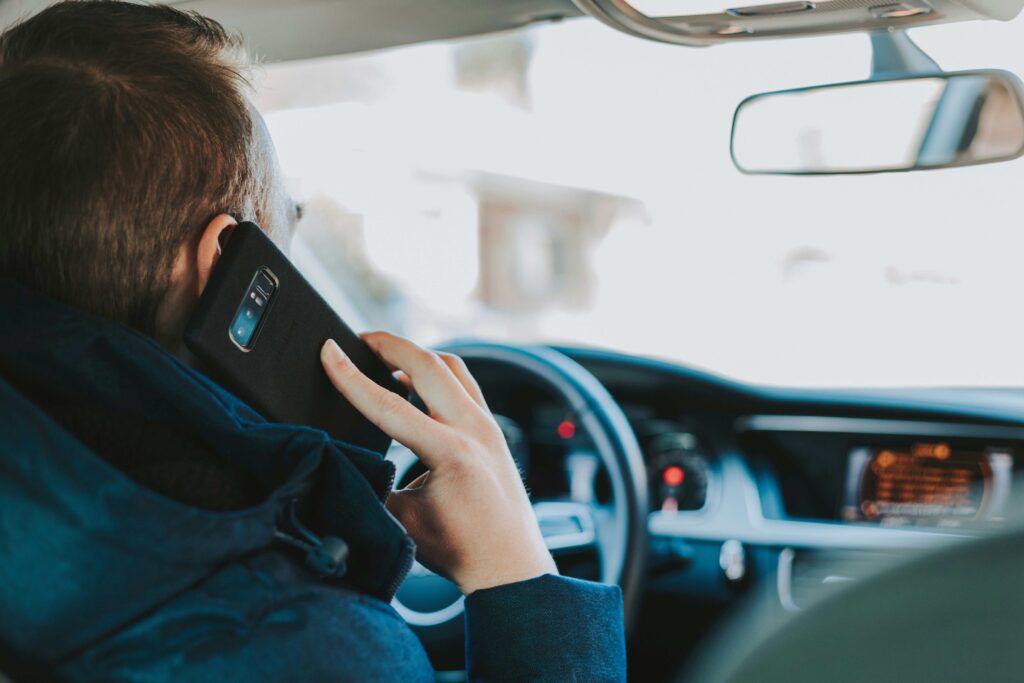 A man secretly talking on phone in car showing workplace friendship boundaries issues. 